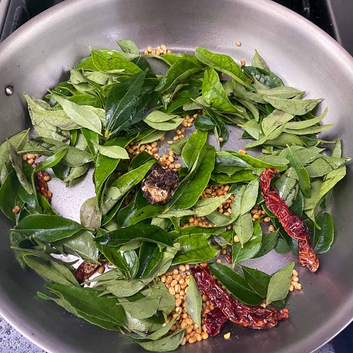 adding curry leaves and tamarind to soften them