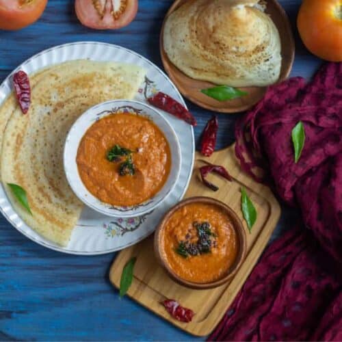 tomato chutney in a wooden bowl and in a ceramic bowl served with dosa