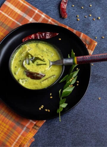 square image of majjige huli served in black bowl on a black plate