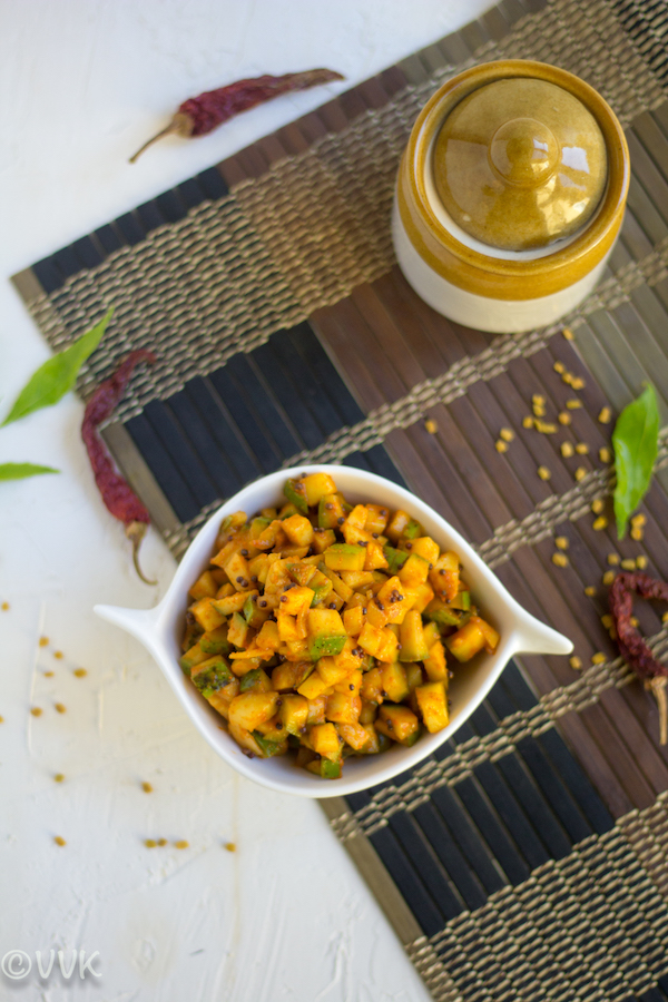 cut mango pickle in a white bowl on a mat