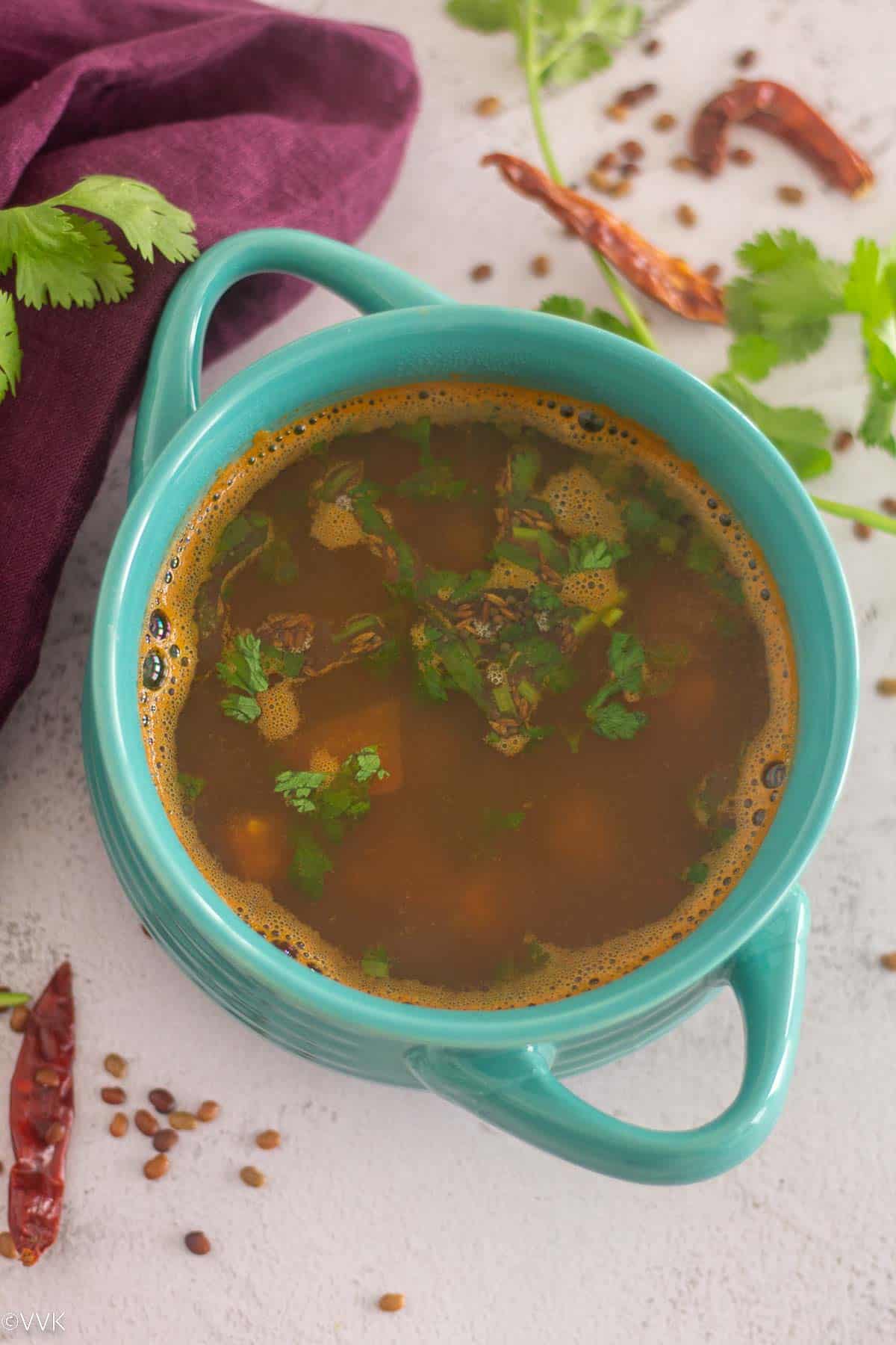 overhead shot of horsegram rasam topped with cilantro