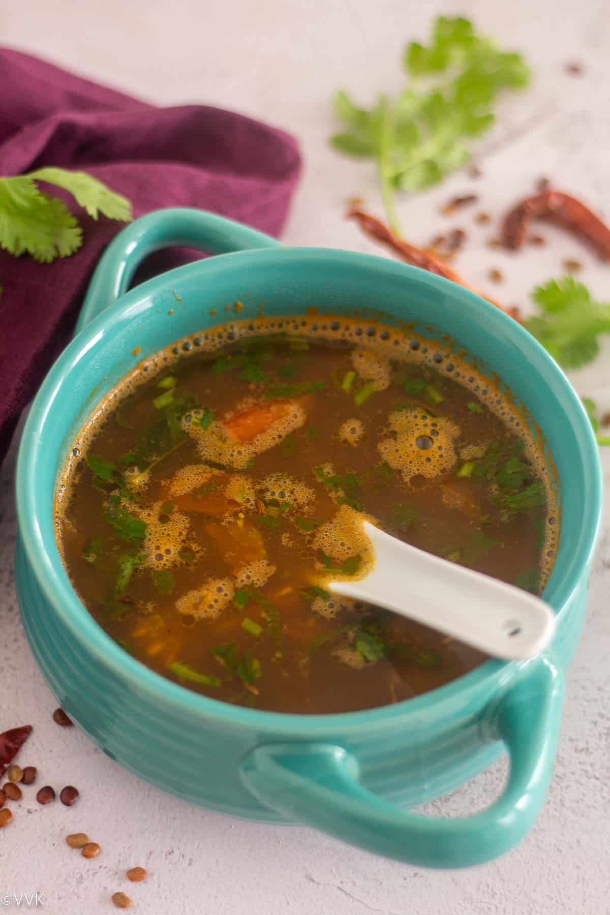 kollu rasam served in blue bowl with spoon inside