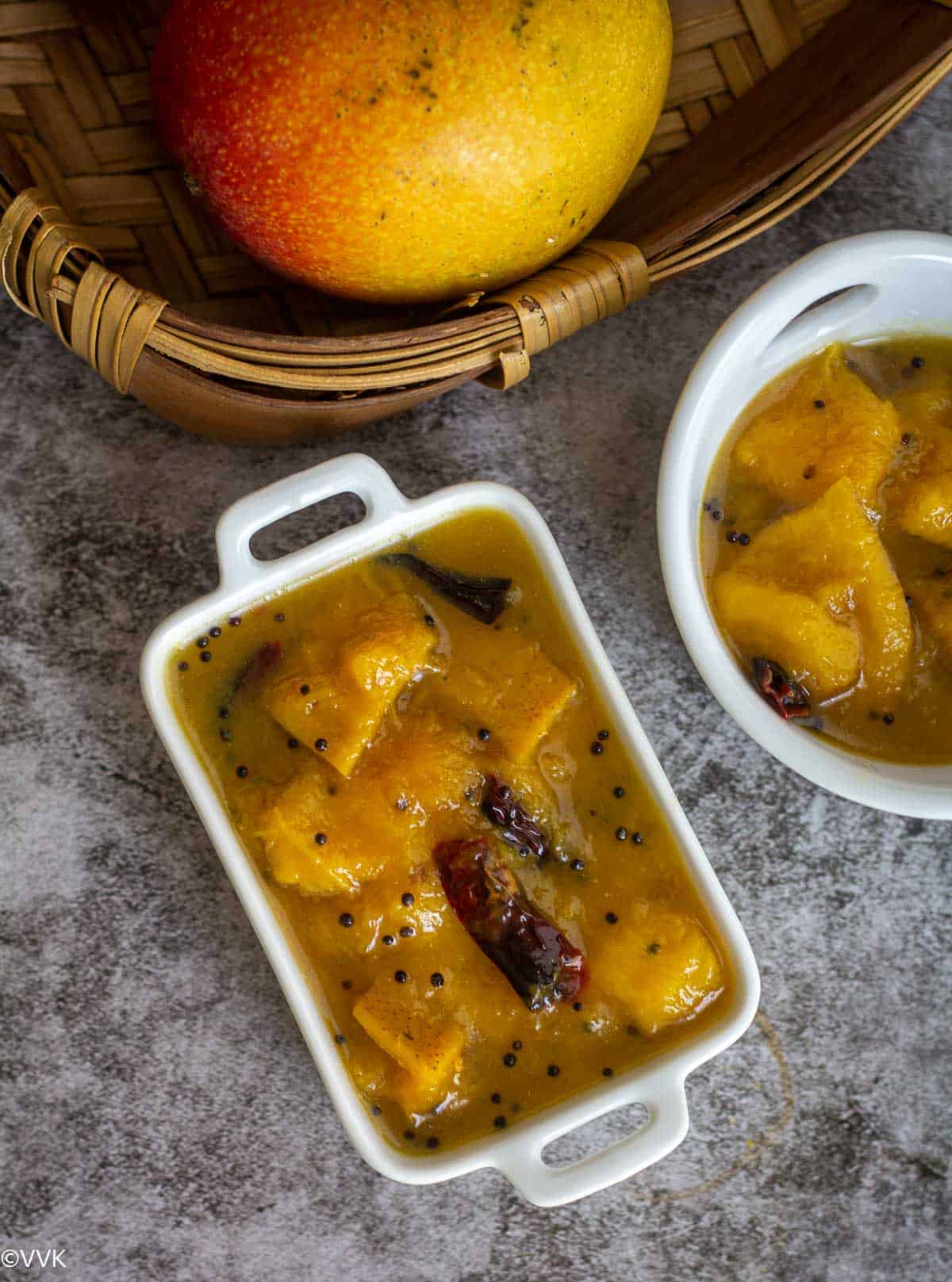 overhead shot of mango relish served in two white bowls with mango on the side