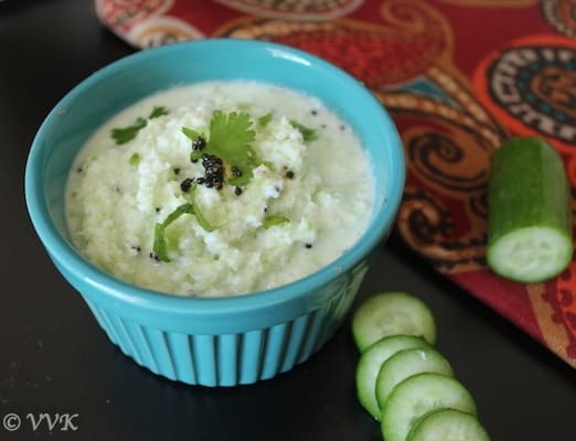 cucumber raita served in a blue ceramic bowl with cucumber slices on the side