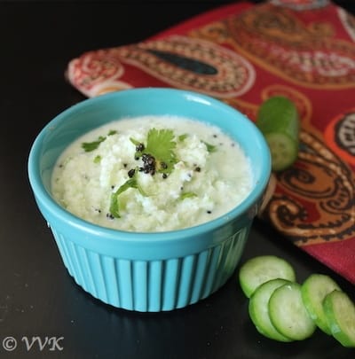 cucumber raita served in a blue ceramic bowl with cucumber slices on the side
