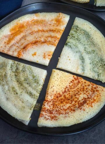 flavored cheese dosa cut into cones placed on a black plate