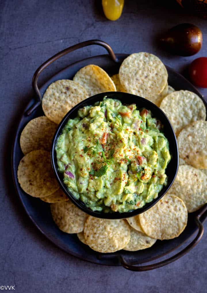 Close up shot of guac served in black bowl with chips