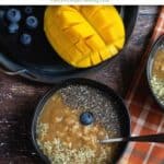 oatmeal served in two black bowls with mangoes on the side with text overlay for pinterest