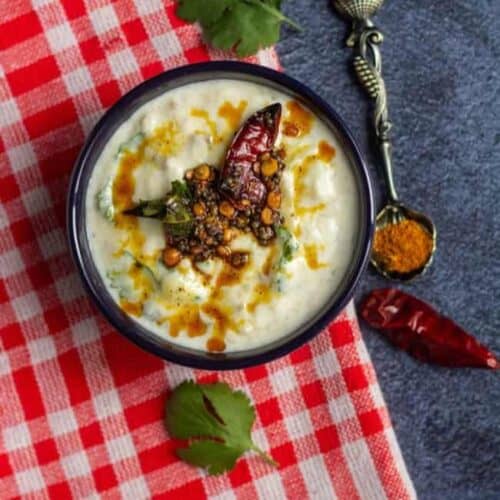 broiled eggplant raita served in a bowl topped with fresh tempering