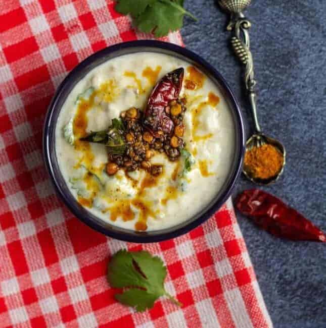 broiled eggplant raita served in a bowl topped with fresh tempering