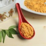 Fresh Coconut Podi presented in a red spoon