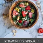 spinach and strawberry salad in a wooden bowl with the dressing on the side with text overlay for pinterest