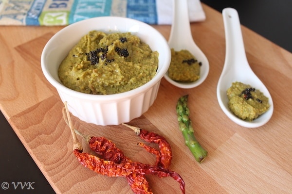 Simple Asparagus Chutney or Asparagus Thogayal in a white bowl and two white spoons with red chilis on a wooden board