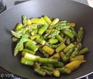 Adding chopped asparagus to a pan and sauteing