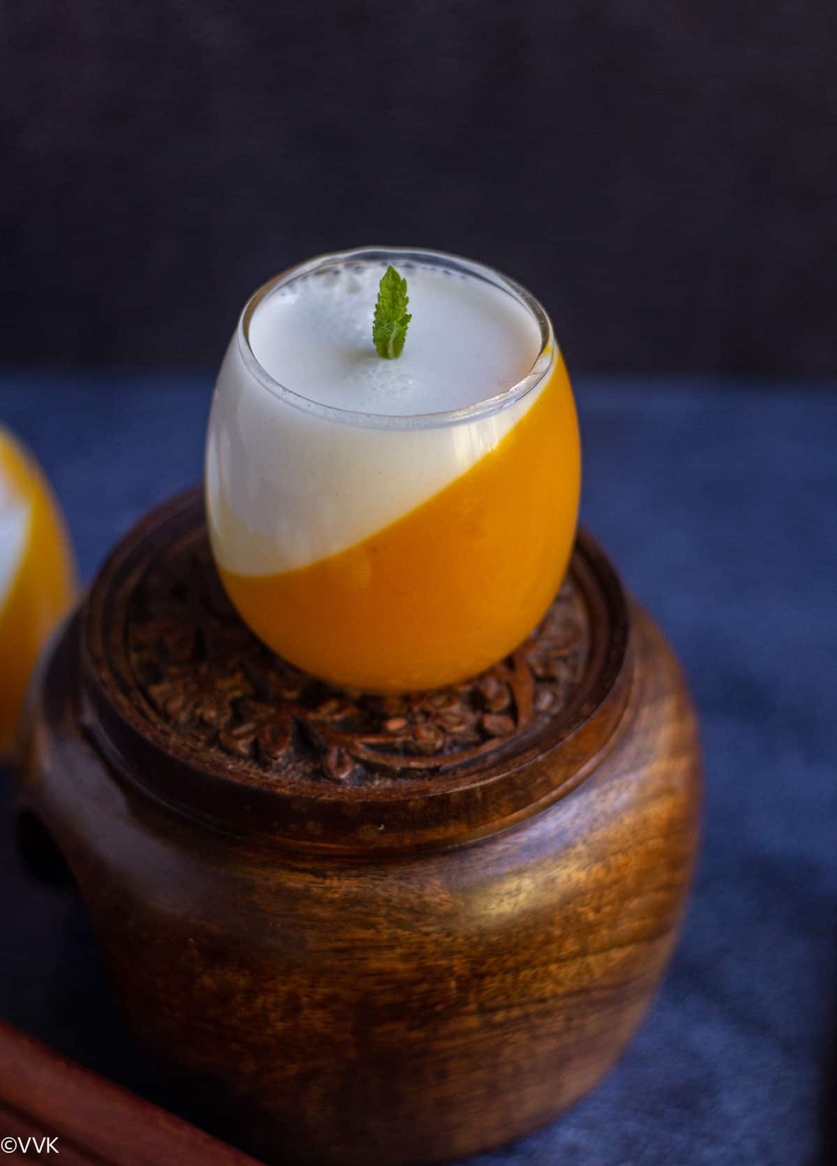 coconut mango jellow served in glass with the layers set in slanting position placed on wooden stand