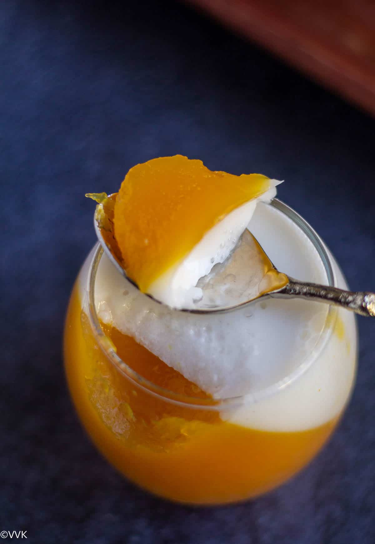a spoon full of mango jelly placed on top of the dessert glass