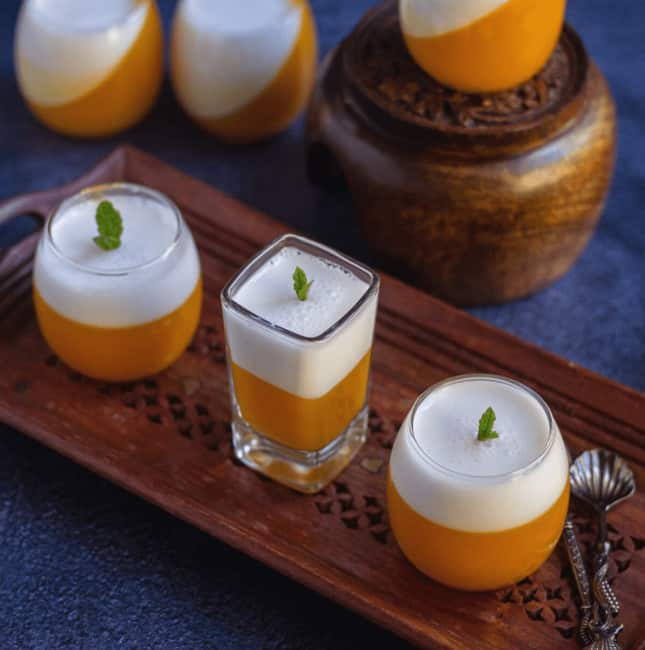 mango coconut jello served in single serve glasses placed on wooden tray