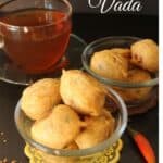 Batata Vada or Indian Potato Fritters served in two glass bowls with a cup of hot drink on the side