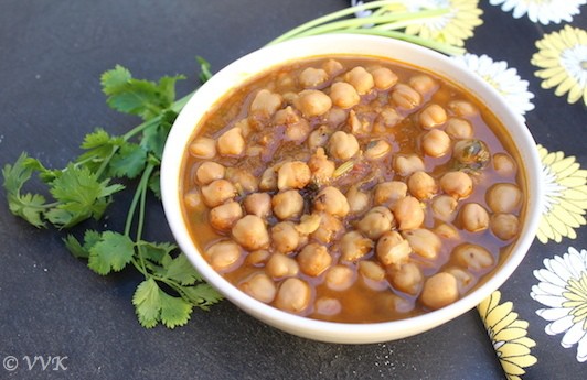 Serving Samosa Chole Chaat in a white bowl with cilantro on the side on a dark surface