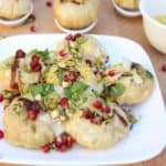 Dahi Sev Puri served on a white plate and decorated with pomegranate seeds