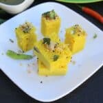 Five pieces of Khaman Dhokla served on a white plate and looking extra delicious
