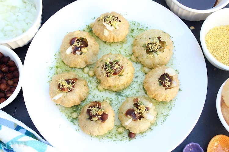 Pani Puri or Golgappas served in green sauce with plenty of sides around the plate