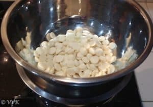 Adding white chocolate to a large metal bowl