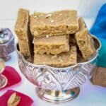 seven cup burfi stacked in bowl with text overlay for pinterest
