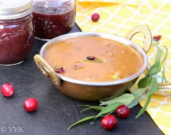 Cranberry Sauce Vathal Kuzhambu served next to cranberry sauce jars and decorated with cranberries