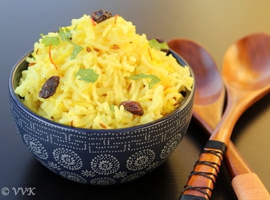 Serving vegan turmeric saffron rice garnished with raisins and cilantro