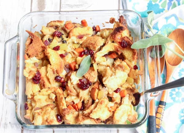 Vegetarian Bread Stuffing Thanksgiving recipe in a big glass casserole with wooden spoons on the side