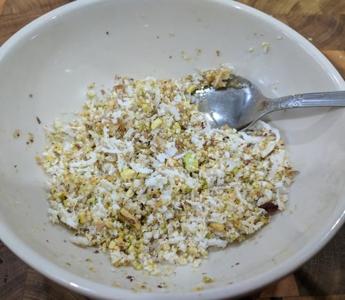 Mixing the grated coconut, ground pistachios, green cardamom powder and honey/nectar together