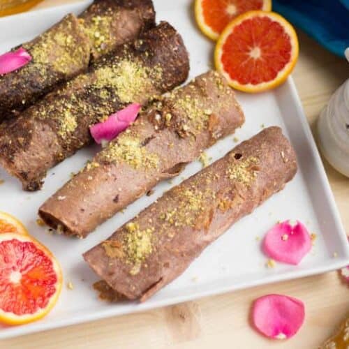 Closeup of the healthy and delicious Ragi Malpua surrounded by orange slices and decorated with beautiful pink petals