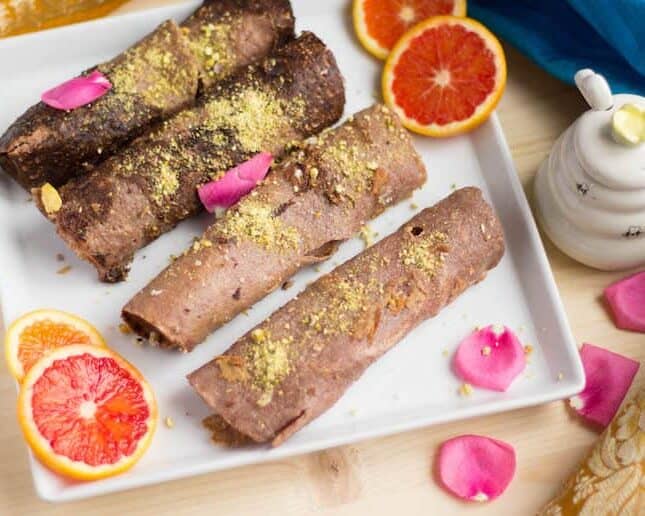 Closeup of the healthy and delicious Ragi Malpua surrounded by orange slices and decorated with beautiful pink petals