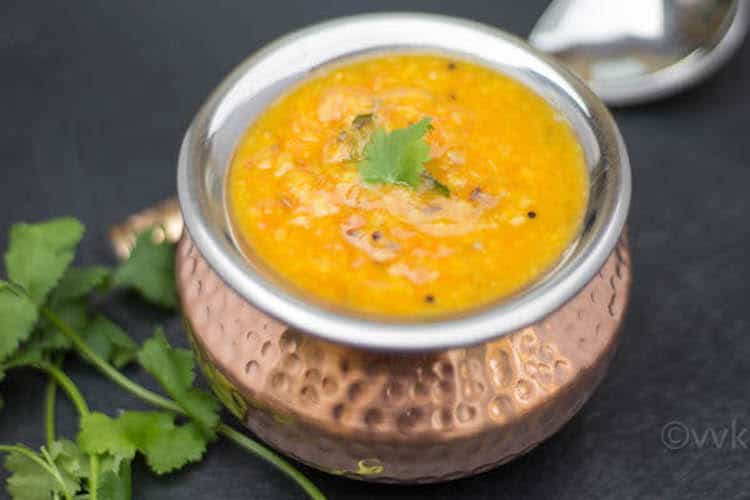 Instant Pot Tomato Pappu Tomato Dal ready and served in a bronze bowl with a spoon blurred in the background