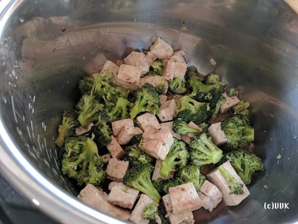 Adding the marinated tofu to the broccoli in a bowl