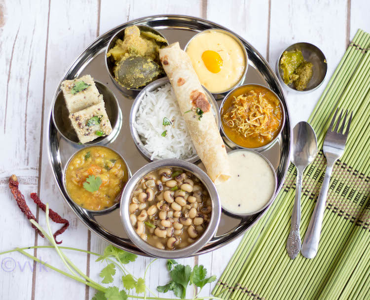 Gujarati Thali served on a tray with a circle shape with a spoon and fork on the side