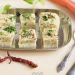 Oats and Rava Dhokla served on a cute metal tray with a fork and a spoon on the table