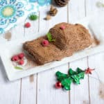 Christmas Special Eggless Yule Log Cake served with raspebrries and cute little Christmas trees