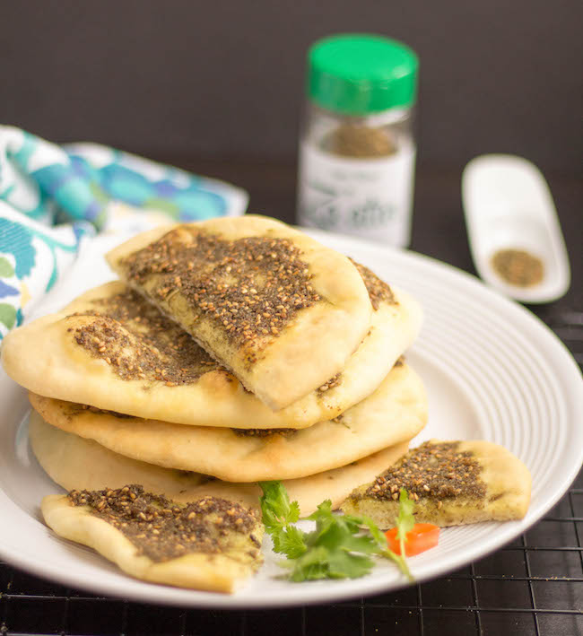 Zaatar bread placed on white plate with some cilantro garnish