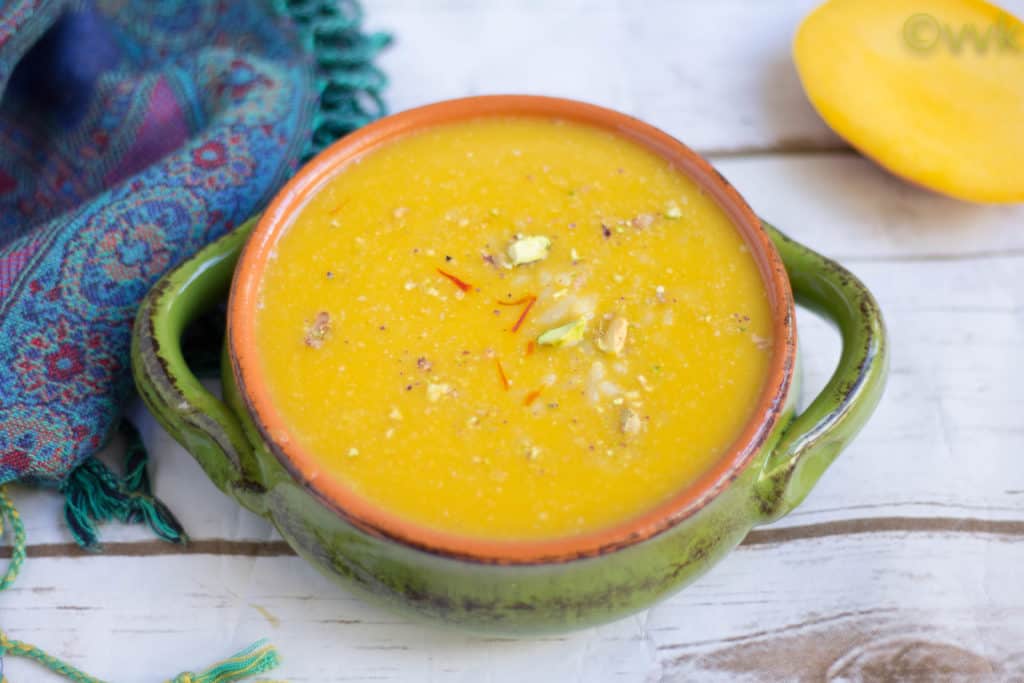 A green bowl of authentic Vegan Mango Phirni looking absolutely delicious