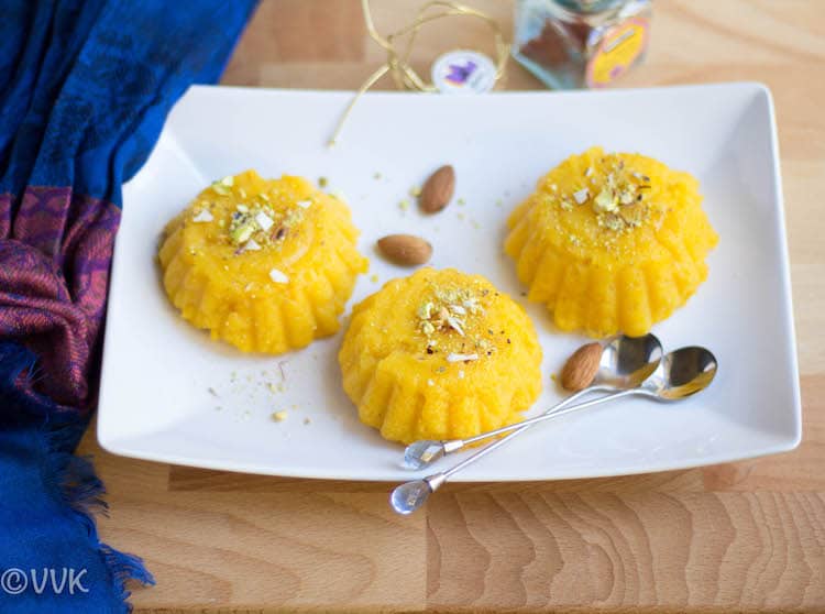 Vegan Mango Kesari or Sheera in a cute white plate with two mini spoons on the table