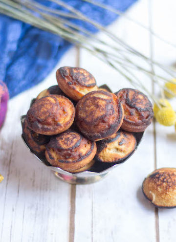 Paniyaram Pan Nei Appam served in a small metal bowl with a nice piece of fabrics on the left