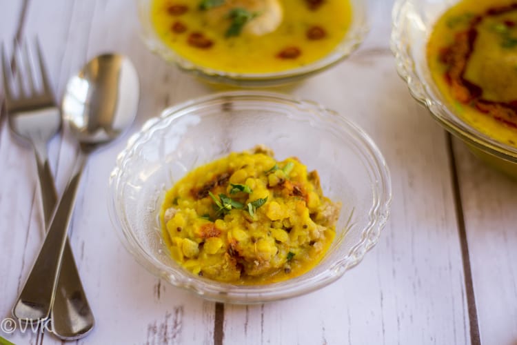 A small glass bowl of the delicious Instant Pot Dal Bafla on a wooden table with a spoon and a fork on the left side