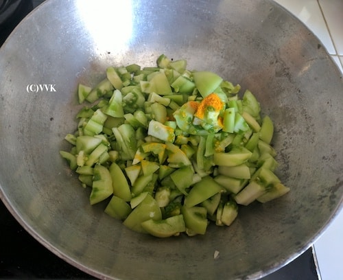 Adding the chopped green tomatoes and turmeric powder