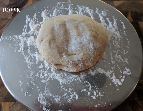 The dough has been transferred to a plate and dusted with flour