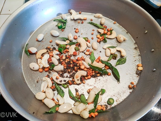 Adding the curry leaves chopped green chilies, cashews and peanuts