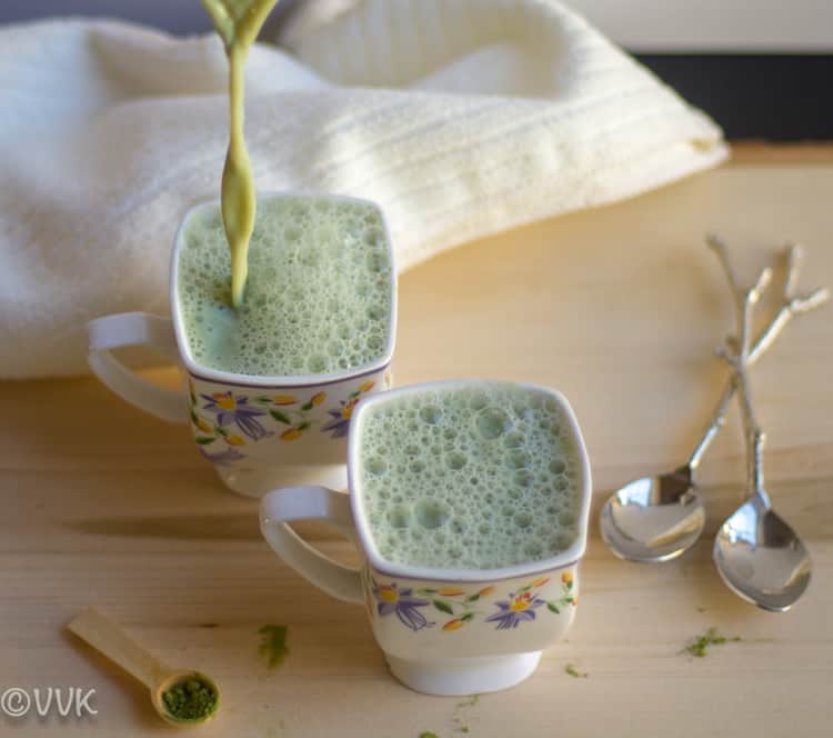 Pouring Matcha Green Tea Latte into a cup with two spoons at the side