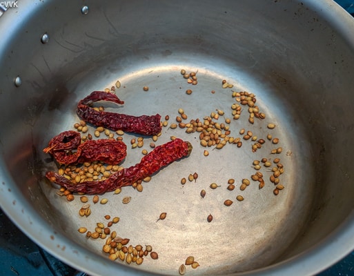 Heating a pan and dry roasting the coriander seeds and red chilies