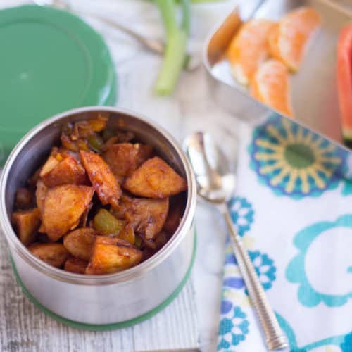 Idli Manchurian served in a cute little box with fruits blurred in the background